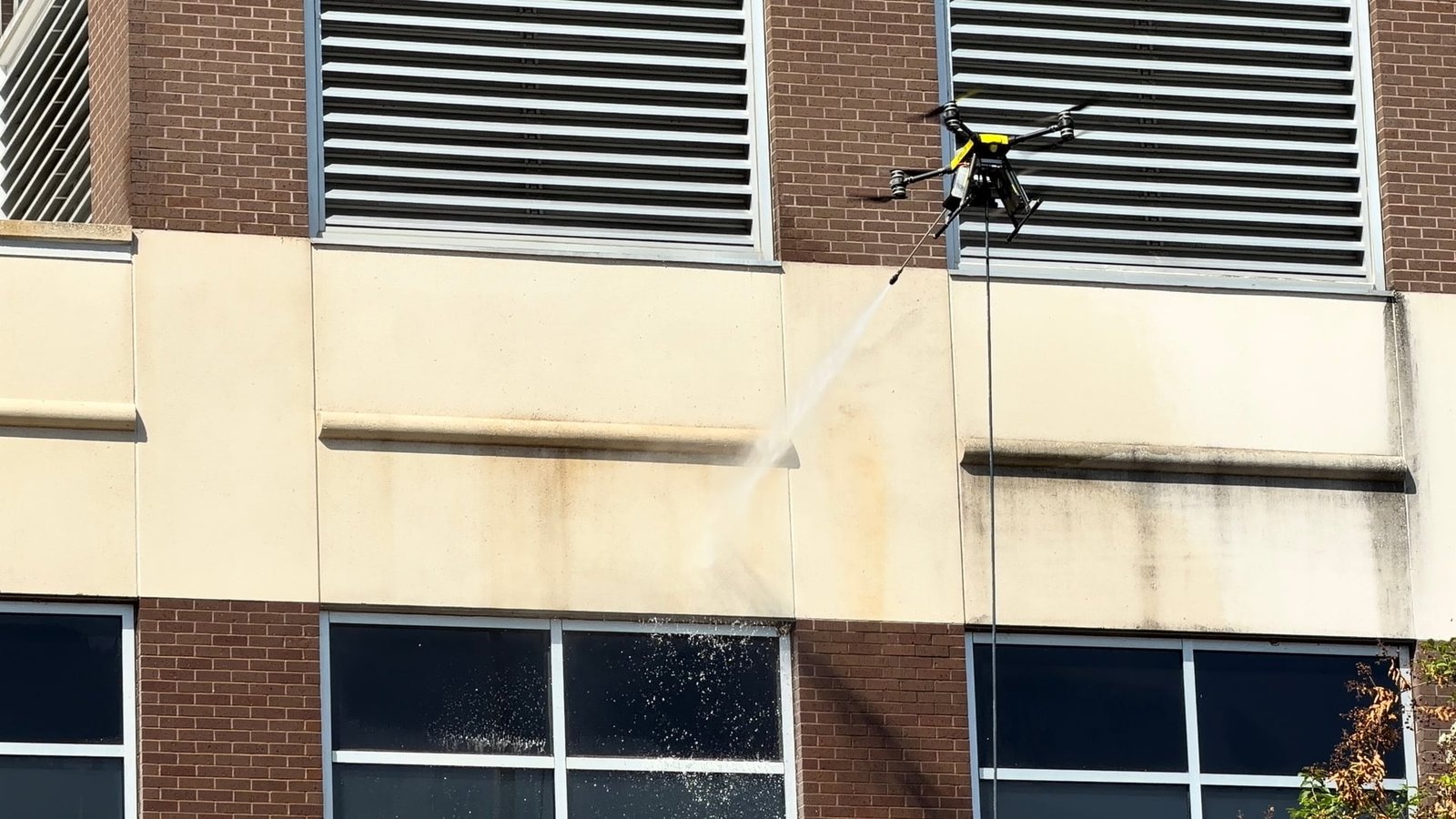 Rotag PT Services cleaning drone applies a controlled rinse to the exterior of a commercial building.