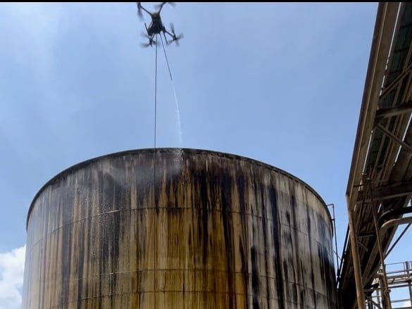 Tethered Rotag PT Services cleaning drone actively rinses the exterior of a large industrial tank.